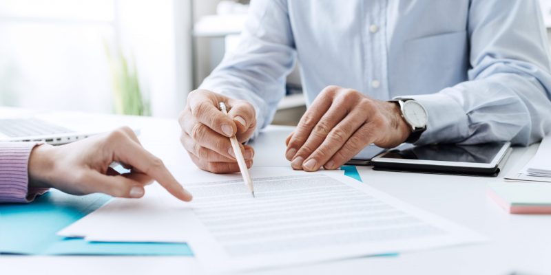 Business people negotiating a contract, they are pointing on a document and discussing together