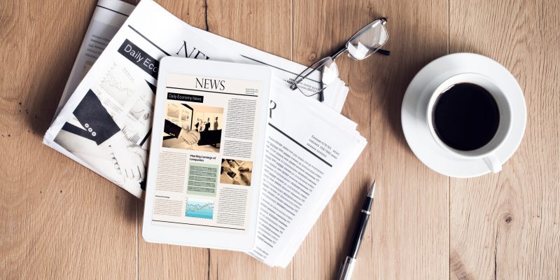 Newspaper with tablet on wooden table